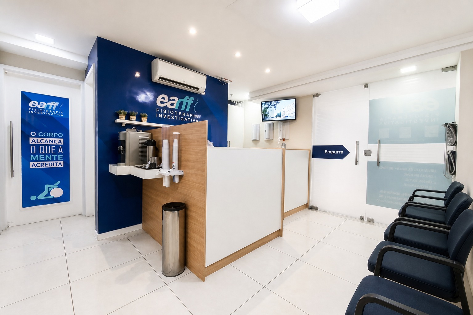 Recepção da unidade EARFF Niterói, balcão de atendimento em madeira e branco com parede azul-petróleo com logo EARFF Fisioterapia Investigativa, cadeiras de espera azul-marinho, ambiente clínico moderno e limpo, iluminação natural, fotografia realista